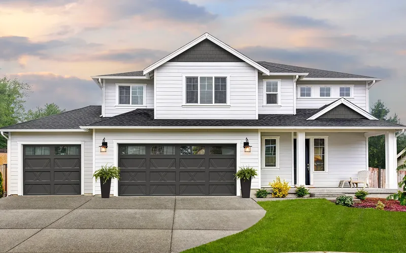 Clopay Bridgeport Inlay dark gray carriage house garage doors on a two-story home