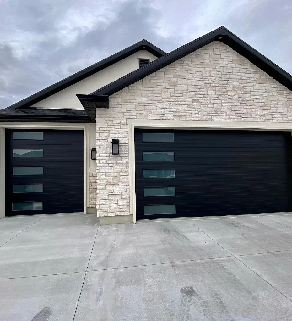 Modern black garage doors with glass panel windows on a stone home