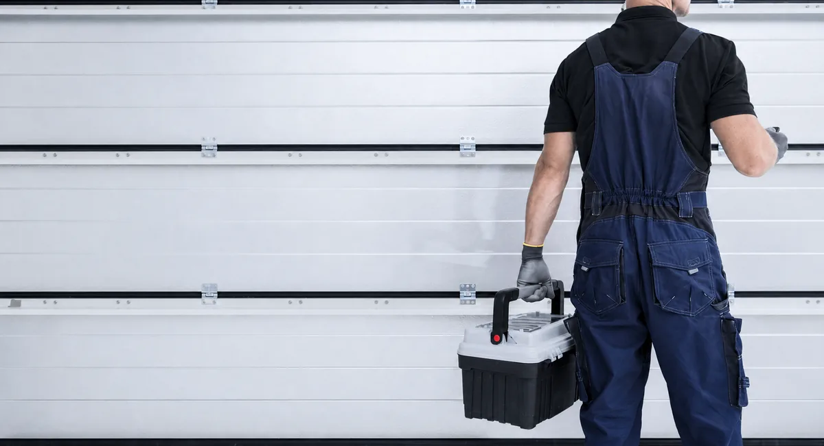 Technician carrying a toolbox in front of a garage door