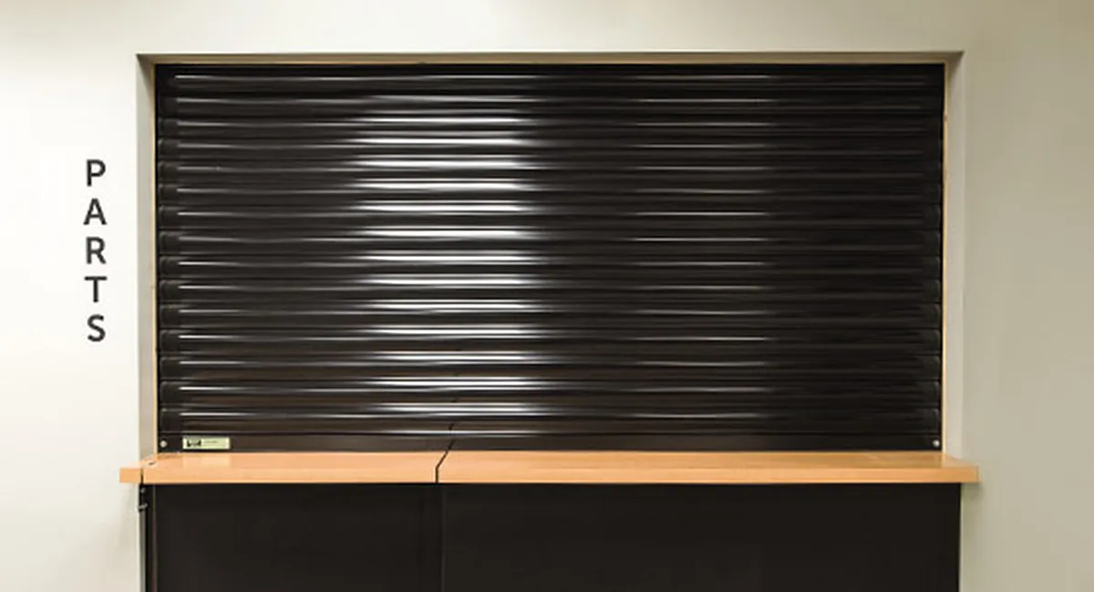 Black commercial rolling security shutter installed over a service window